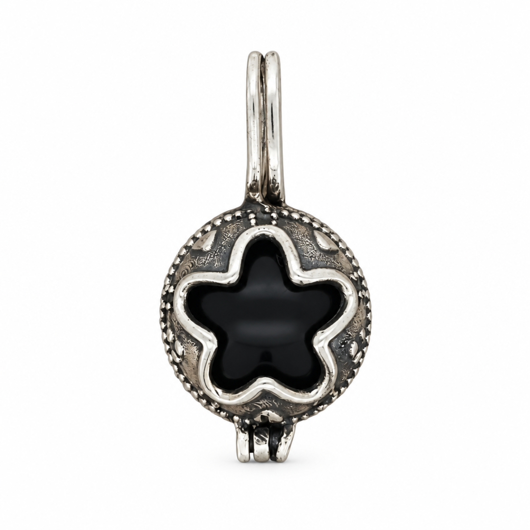 Dije Gotland de plata ley 925 con centro negro de contorno floral sobre fondo blanco.